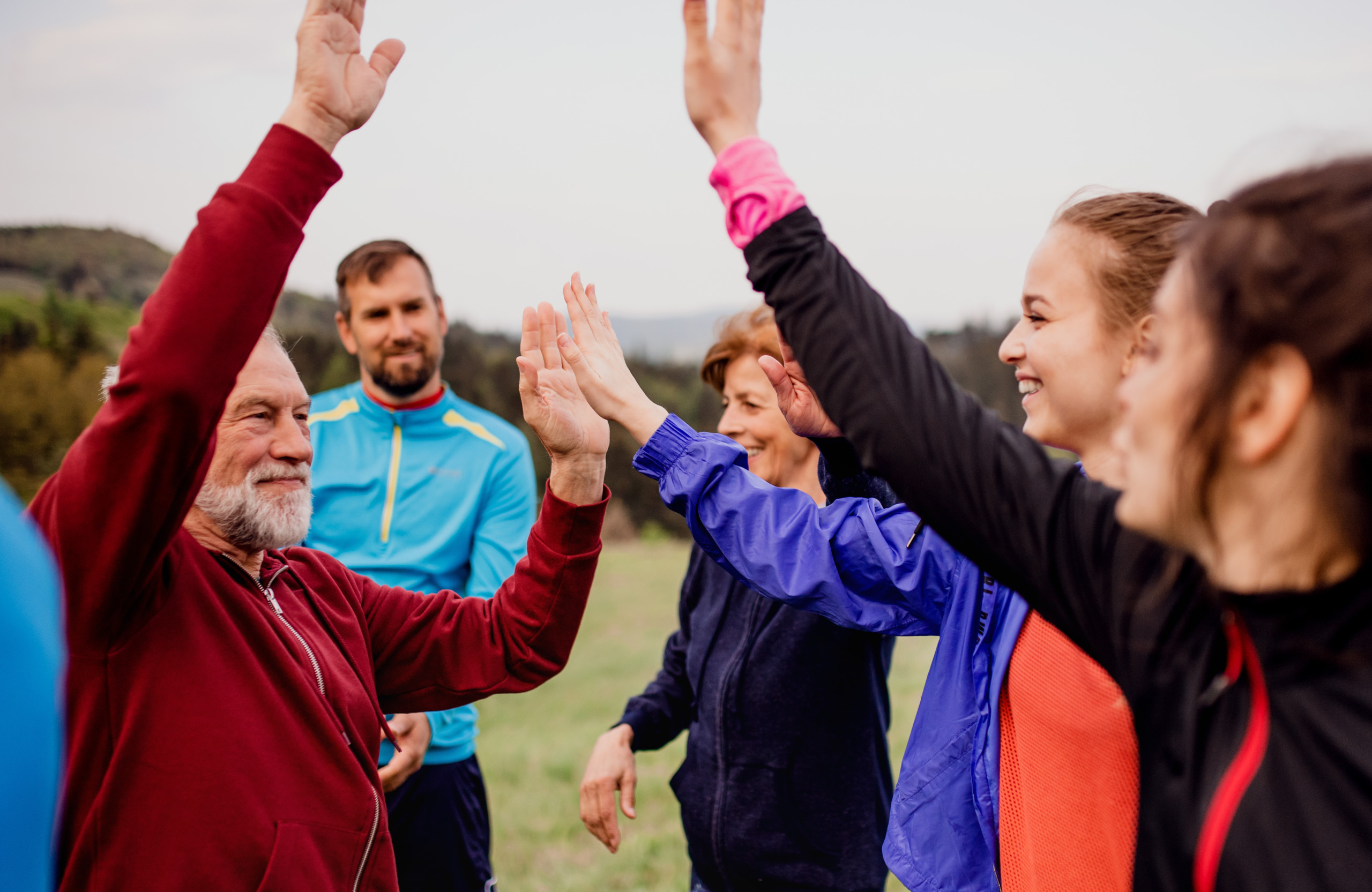 Large group of fit and active people resting after doing exercise in nature.